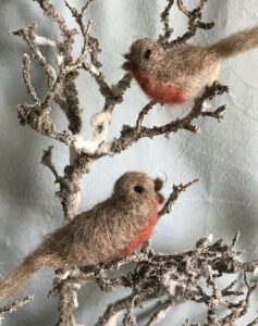 zwei gefilzte Rotkehlchen sitzen auf einem schneebedeckten Zweig