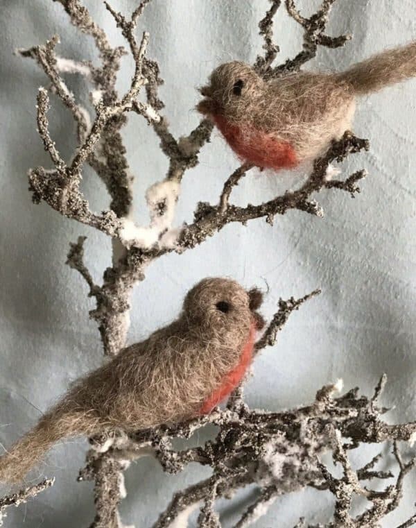 zwei gefilzte Rotkehlchen sitzen auf einem schneebedeckten Zweig