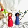 Zwei Blumenkinder aus Filz nebeneinander – Himbeerkind in Rot und Heidelbeerkind in Blau, handgefilzte Jahreszeitenfiguren für den Sommer-Jahreszeitentisch
