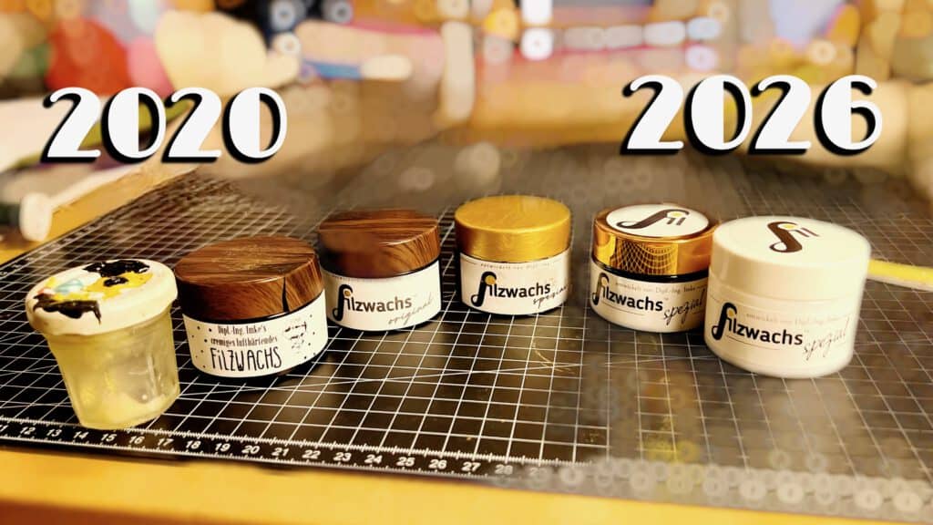 Sechs Filzwachs-Tiegel in einer Reihe auf einer Schneideunterlage, beschriftet mit 2020 links und 2026 rechts – von der ersten Charge im Marmeladenglas bis zum neuen weißen Opalglas-Tiegel Filzwachs Spezial, dazwischen alle Entwicklungsstufen mit Logo-Entstehung​​​​​​​​​​​​​​​​